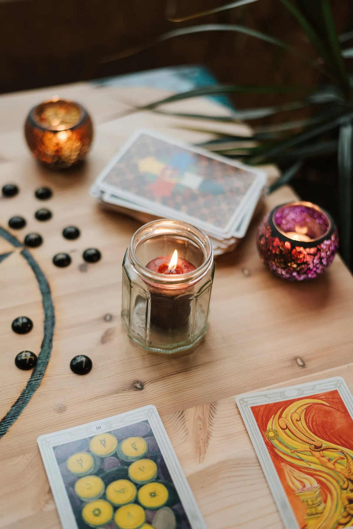 Candles glowing beside a stack of tarot cards on a table