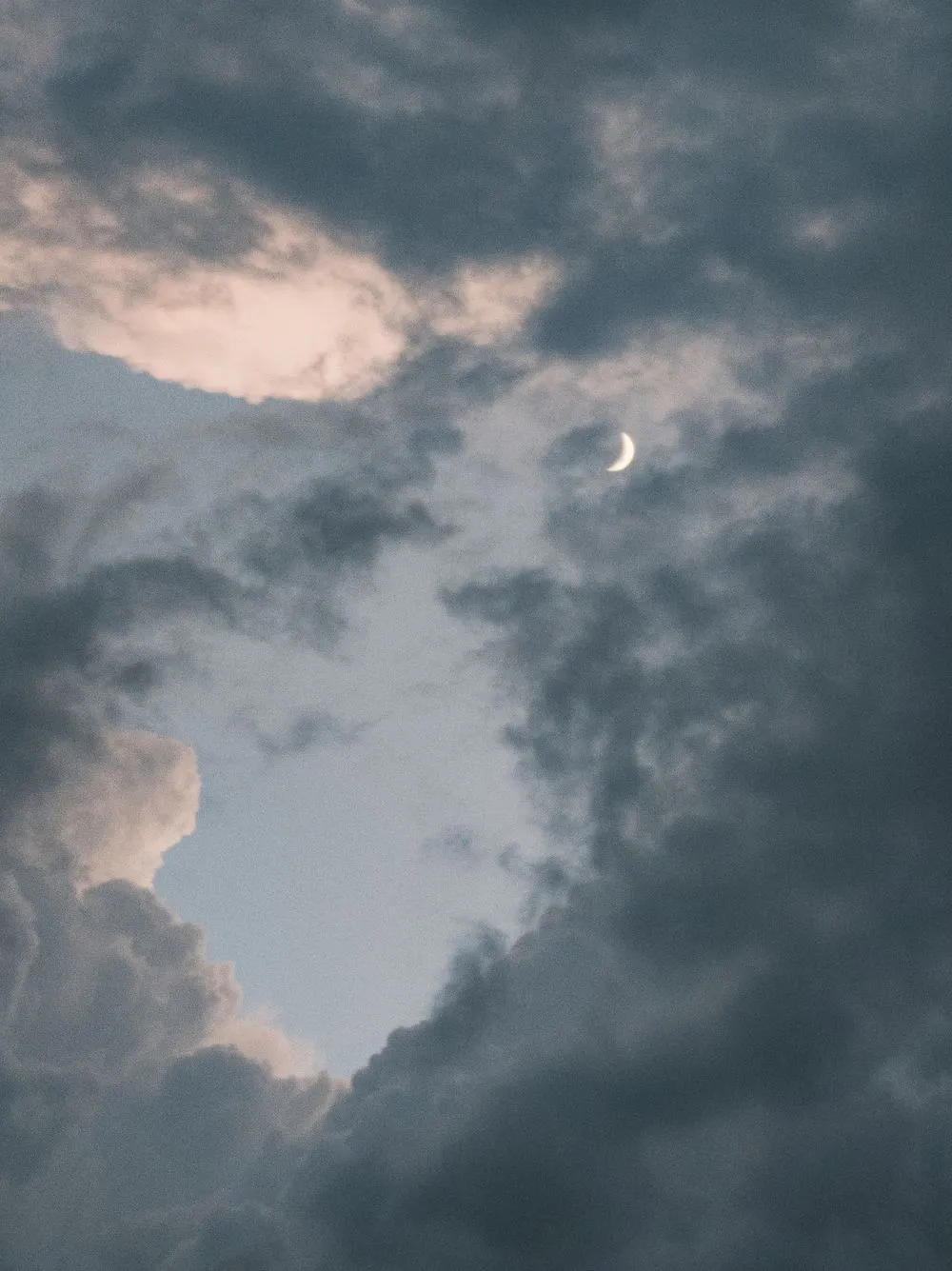 Crescent moon glowing through dramatic night clouds, evoking the mystery of dreaming about someone before you meet them