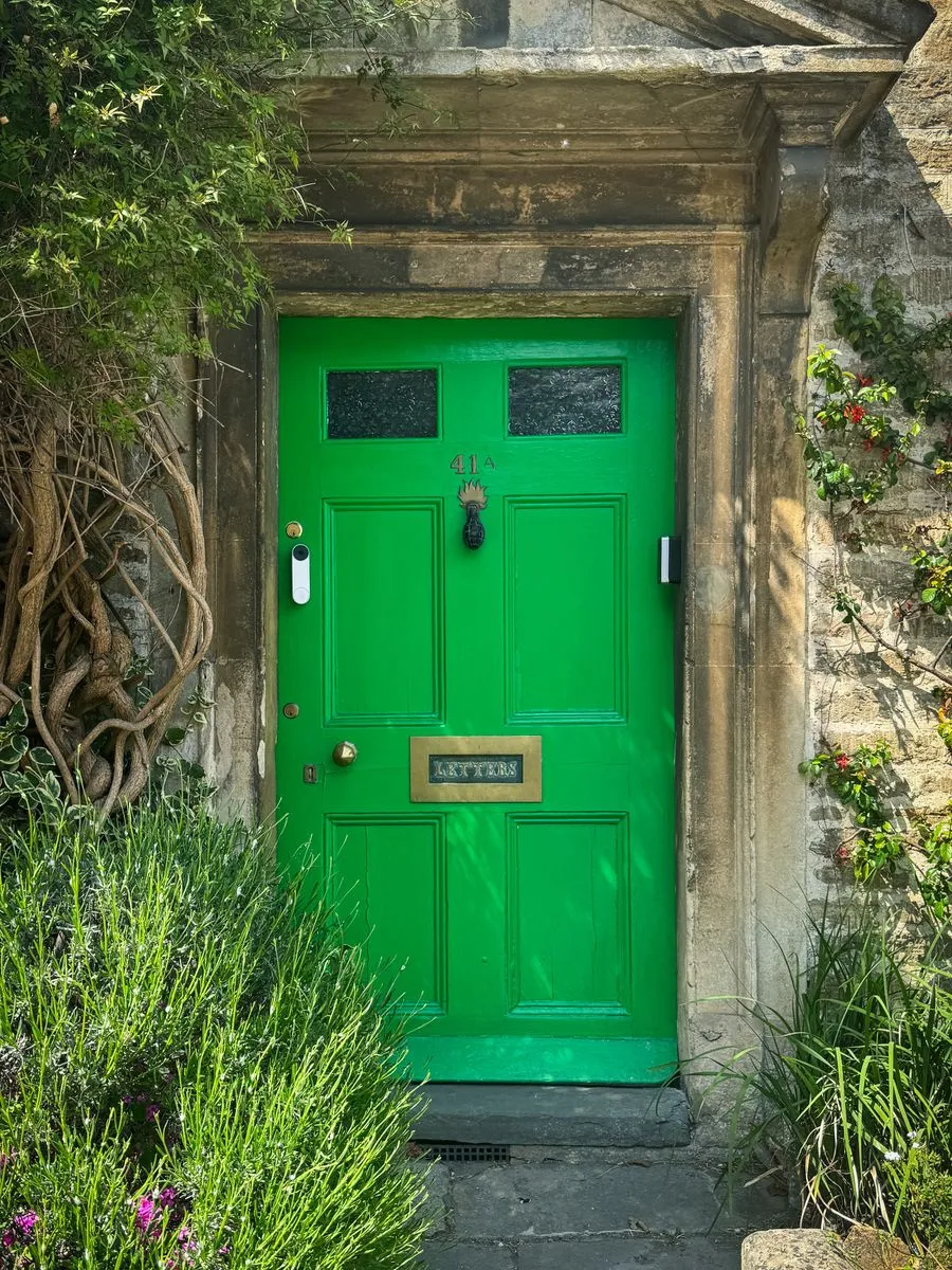 A charming green front door surrounded by countryside greenery