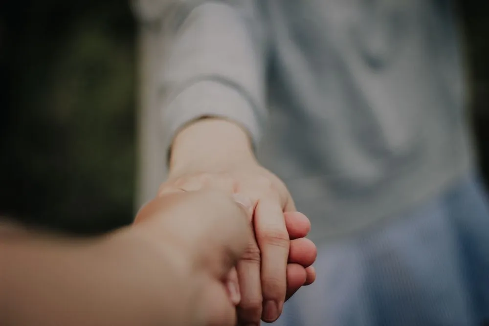 Two hands holding in a gesture of connection and support