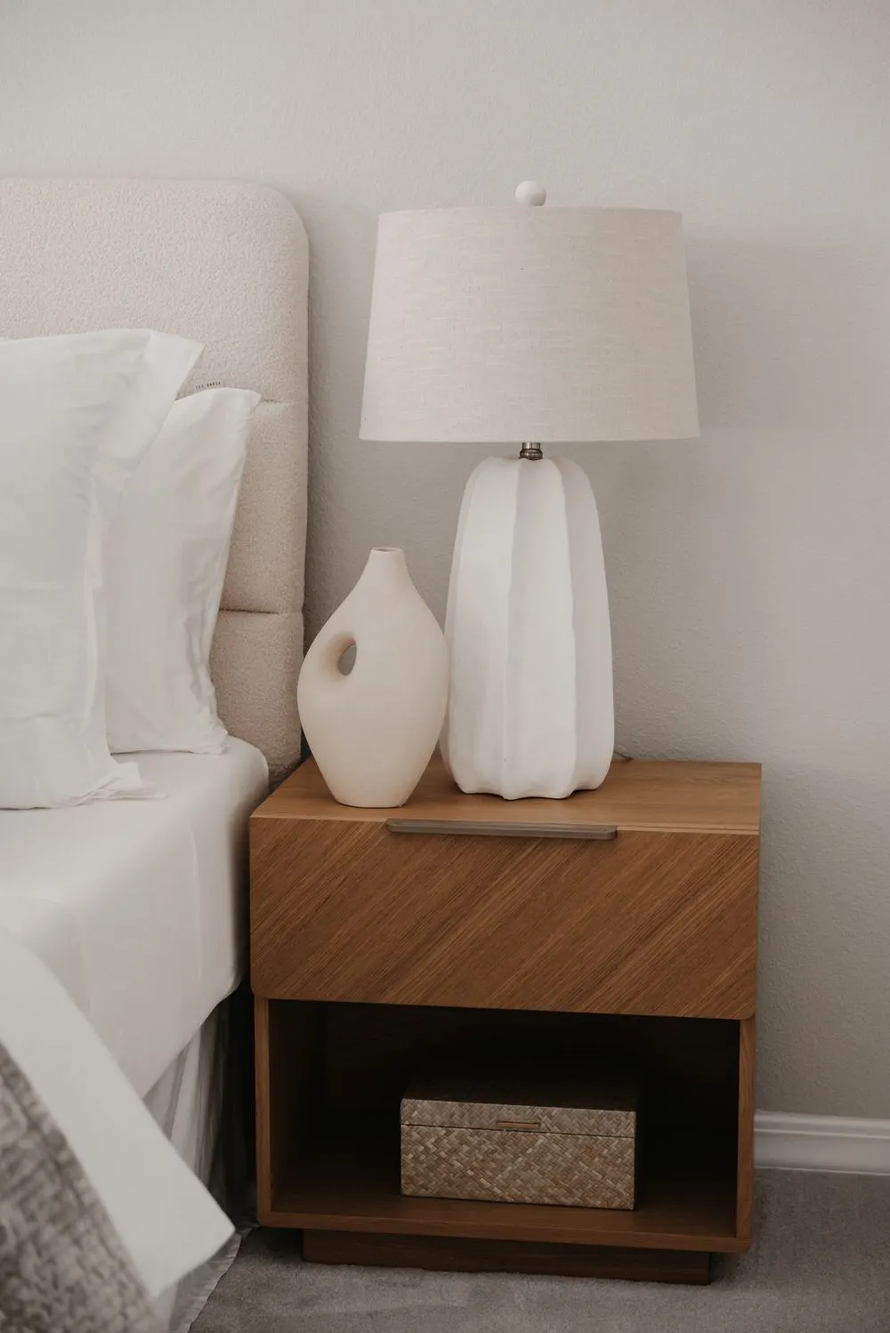 A minimalist nightstand with a soft lamp and decorative vase