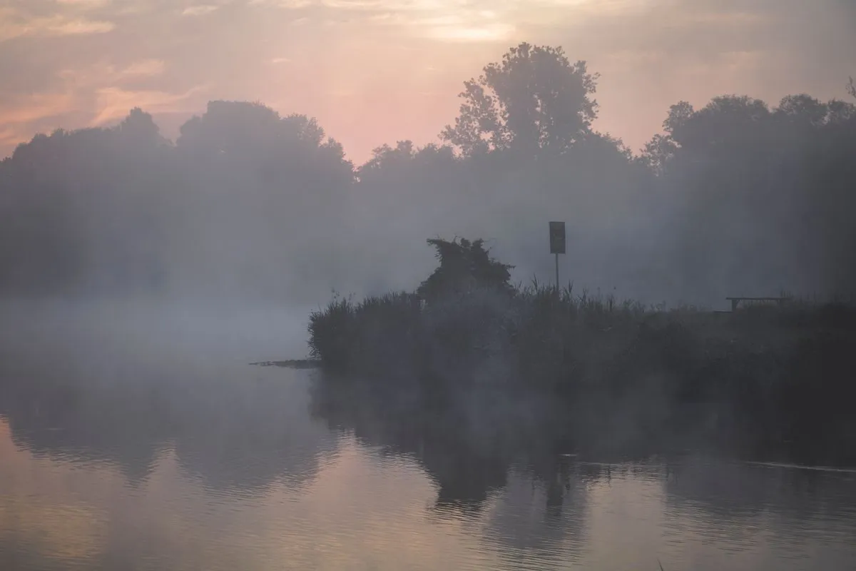 A misty sunrise over a tranquil lake surrounded by trees