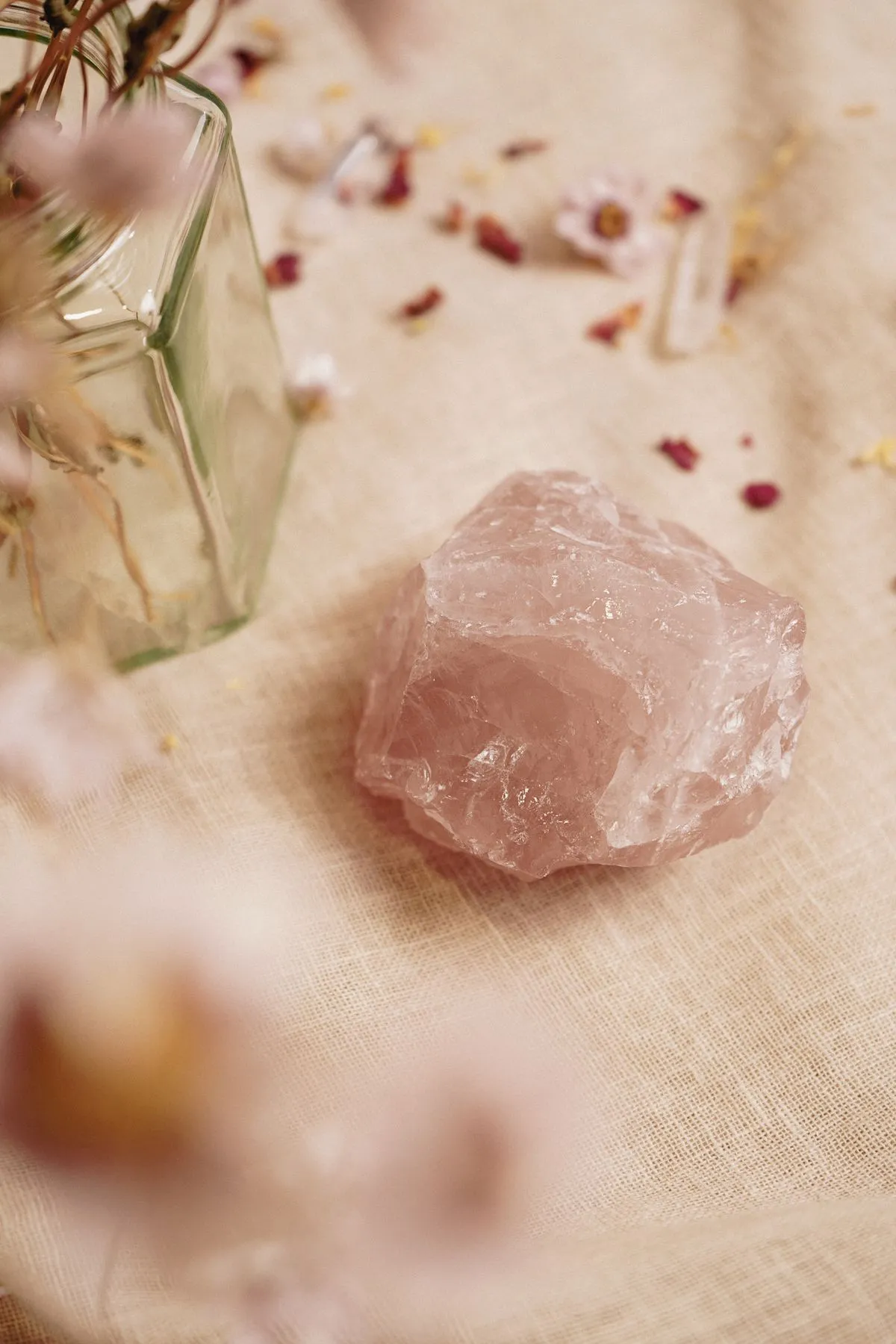 Rose quartz crystal resting among delicate flowers on soft fabric