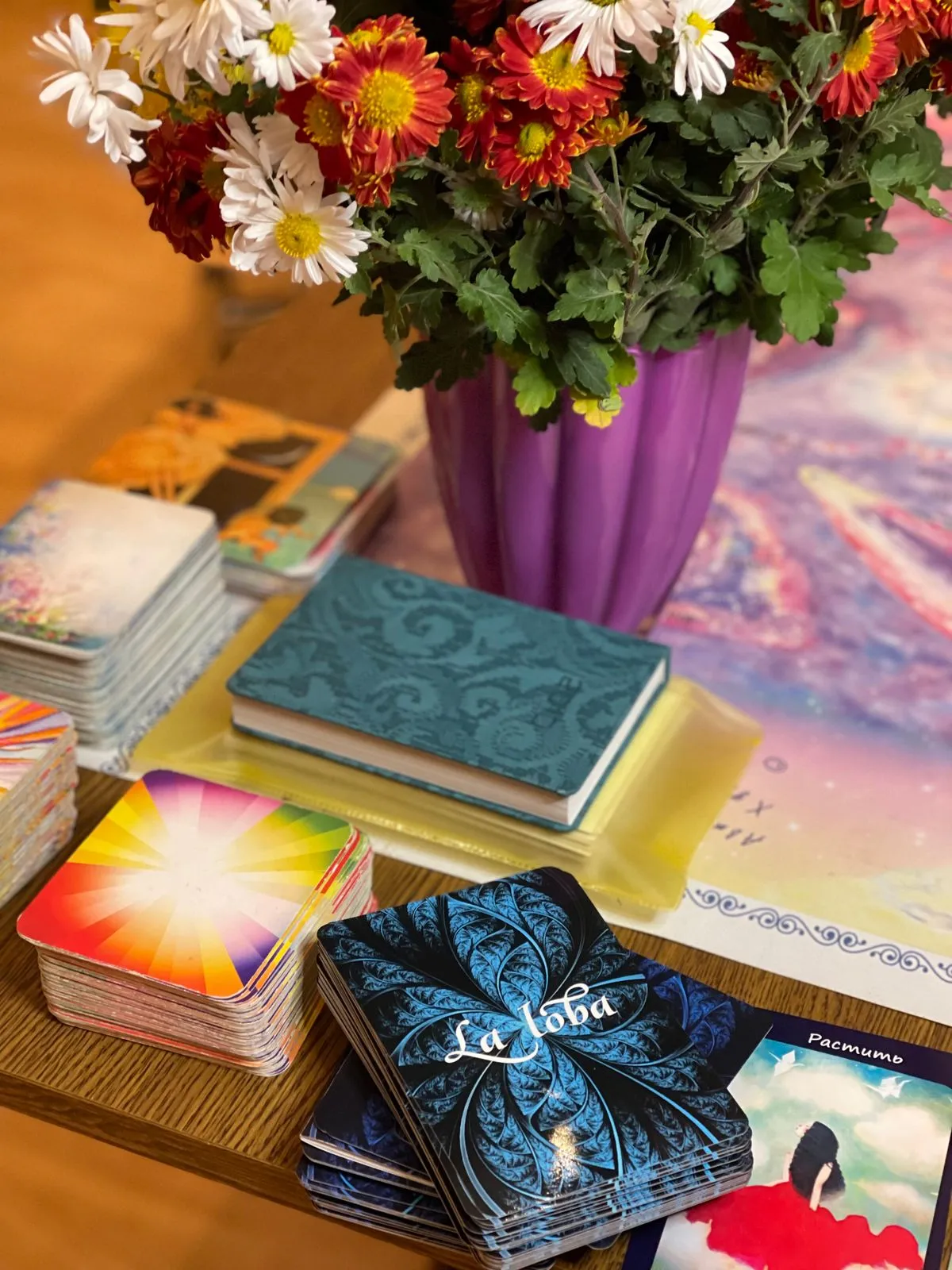 A journal, tarot cards, and flowers arranged together for reflection