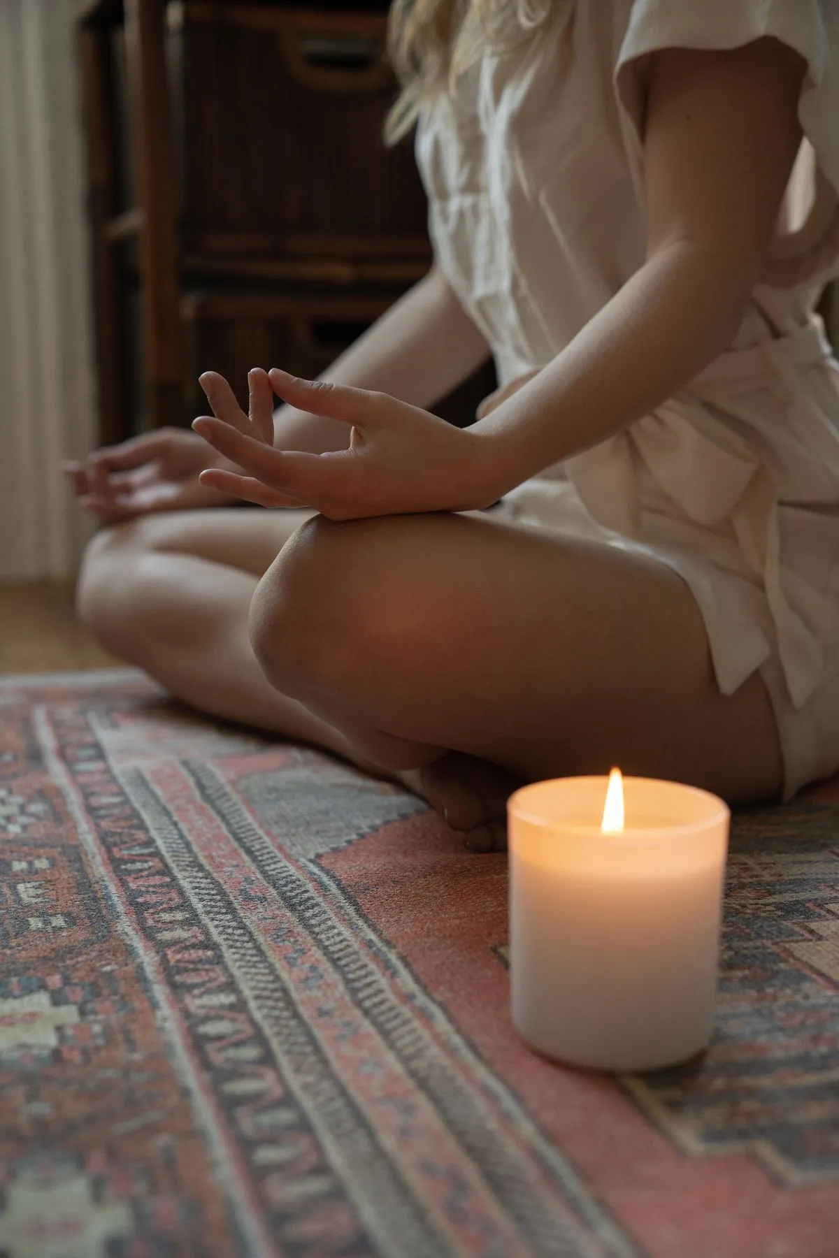 A woman meditating calmly by candlelight